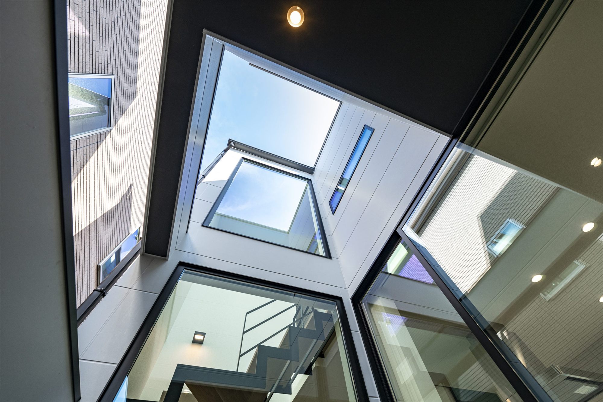 間口6.3mの縦長の敷地に建つ家の中庭から、ガラス越しに空を見上げる(ARCHI PRODUCTS 設計・施工)